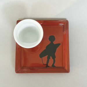 assiette revol en porcelaine noire et emaillée en rouge avec le surfeur