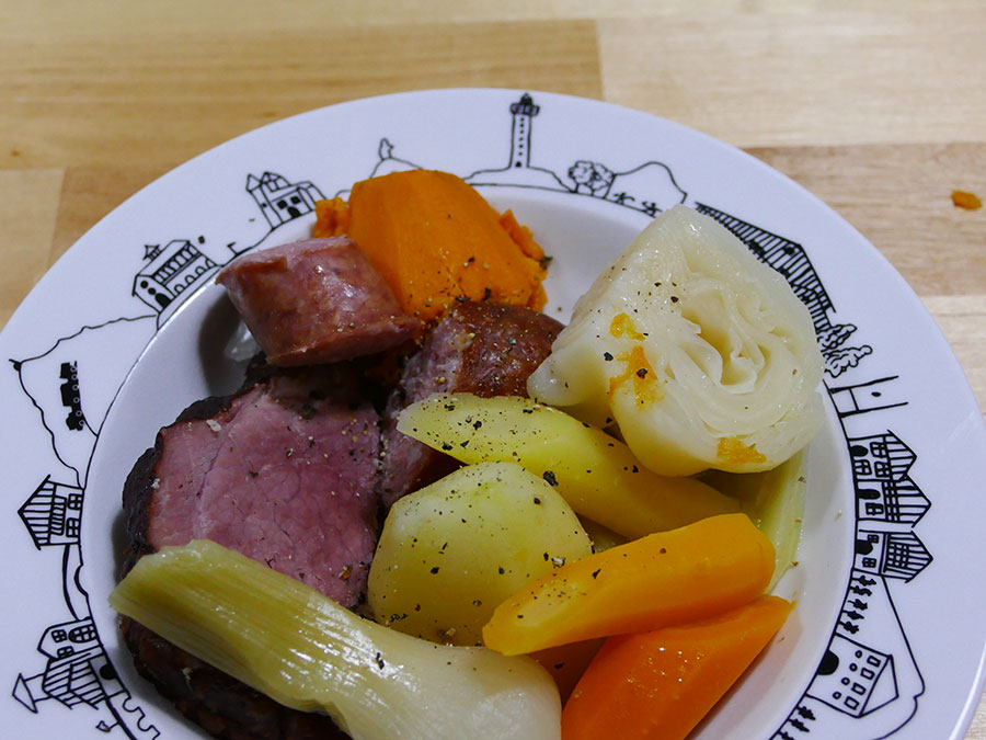 recette de la potée une vrie recette d'hiver avec des carottes multicolores et des patates douces, côté viande, des saucisses fumées, le tout présenté dans une assiette à soupe basque éditée par la manufacture revol, made in france