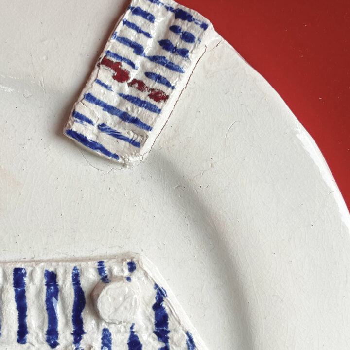 la salopette raoyé est une pièce unique très originale, les lignes bleurs et la ligne rouge sont dessinées et émaillées à la main par béatrice pene lassus pour assiettes et compagnie